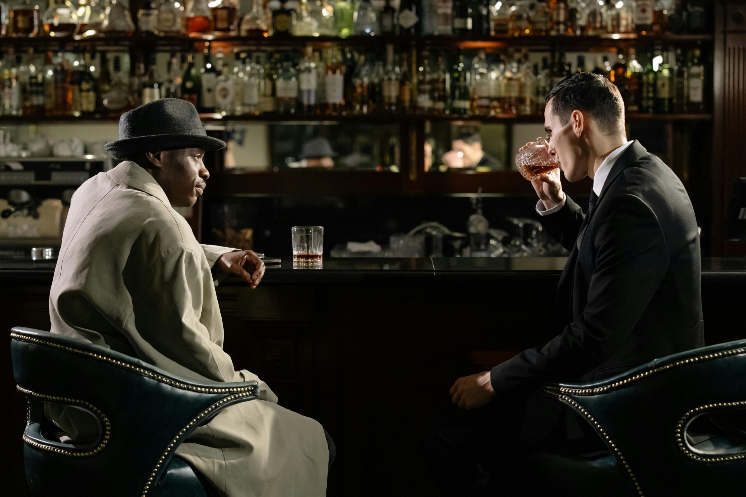 two men sitting at a bar drinking